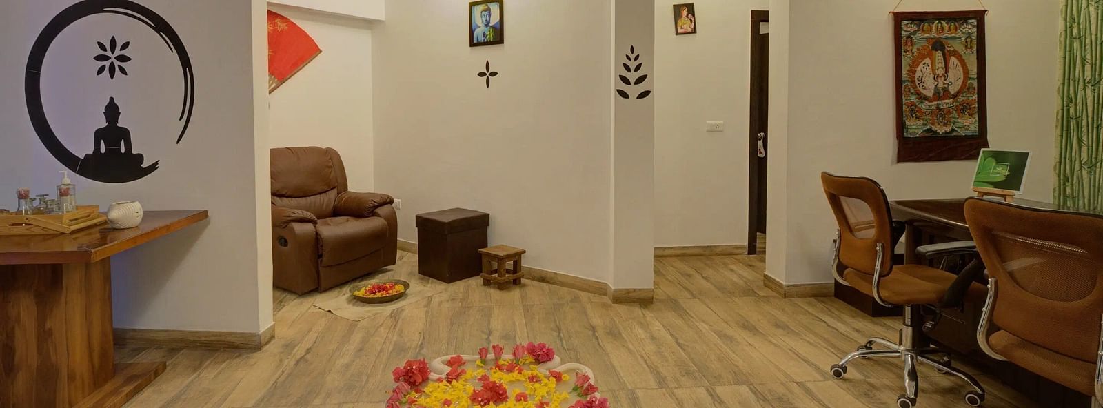 Modern interior with wooden floors, Buddha silhouette, lounge chair, desk, and a flower arrangement.-Bamboo Saa, Udaipur