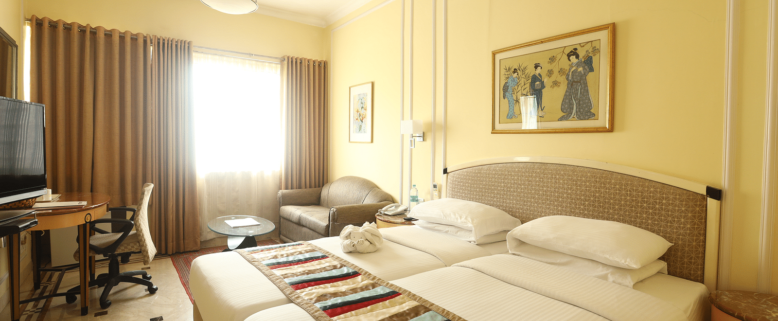 Twin beds in the Superior Room with sunlight peeking through the windows at Regency Hotel, Mumbai.