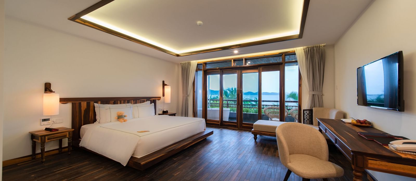 A hotel room with wooden flooring, a plush bed and multiple amenities for enjoyment - Alibu Resort Nha Trang