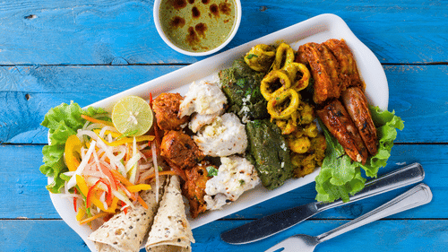 A platter of food is shown from a different angle on the blue wooden table.