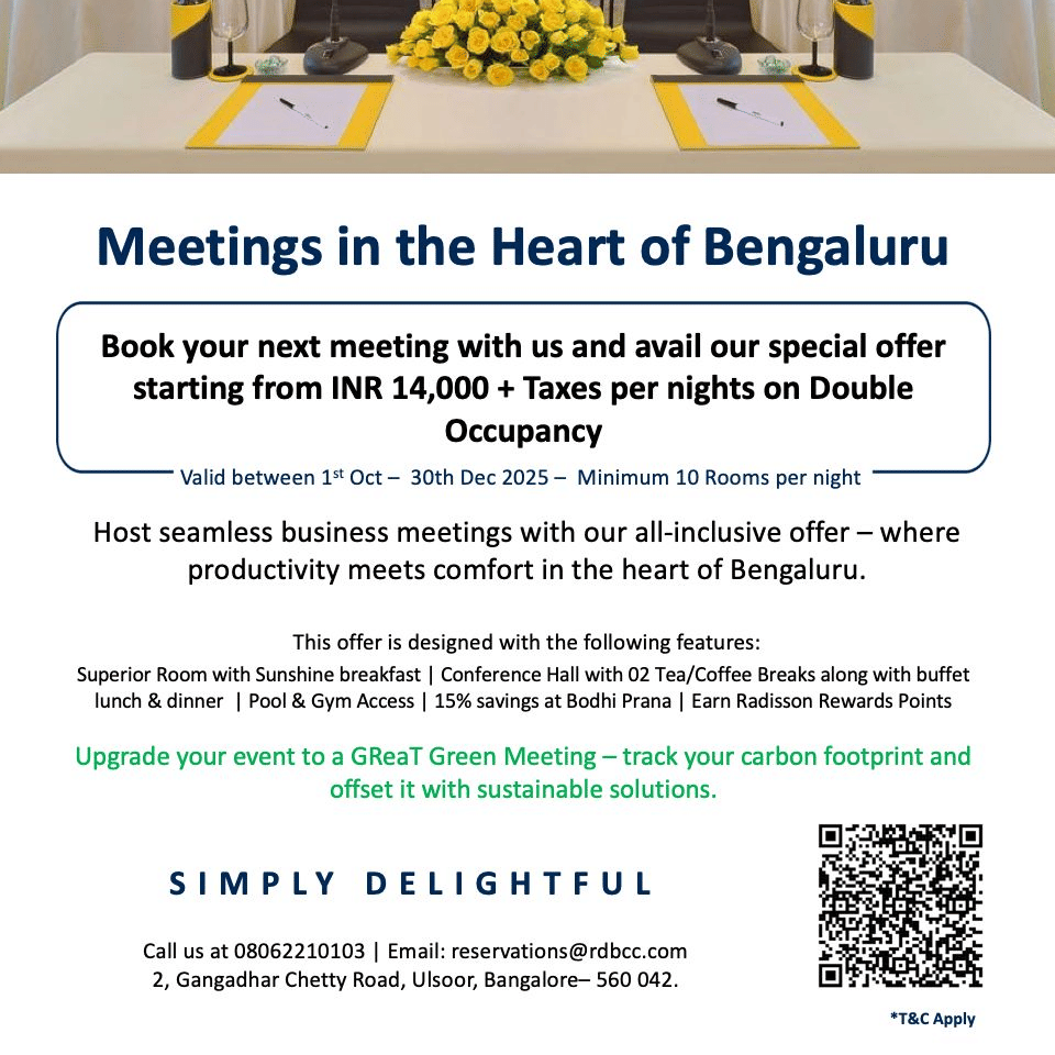 A modern conference room at Radisson Bengaluru with neatly arranged tables, floral centrepieces and meeting materials promoting a special business meeting offer.