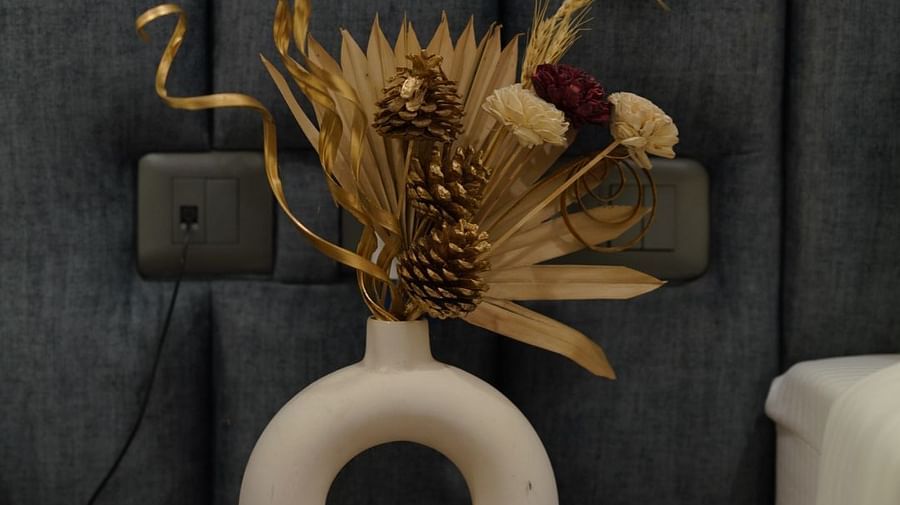 A close-up of a decorative golden sculpture on a bedside table, placed against a headboard at Hotel Kyzen Smartstays – Smart, Reliable, Kyzen