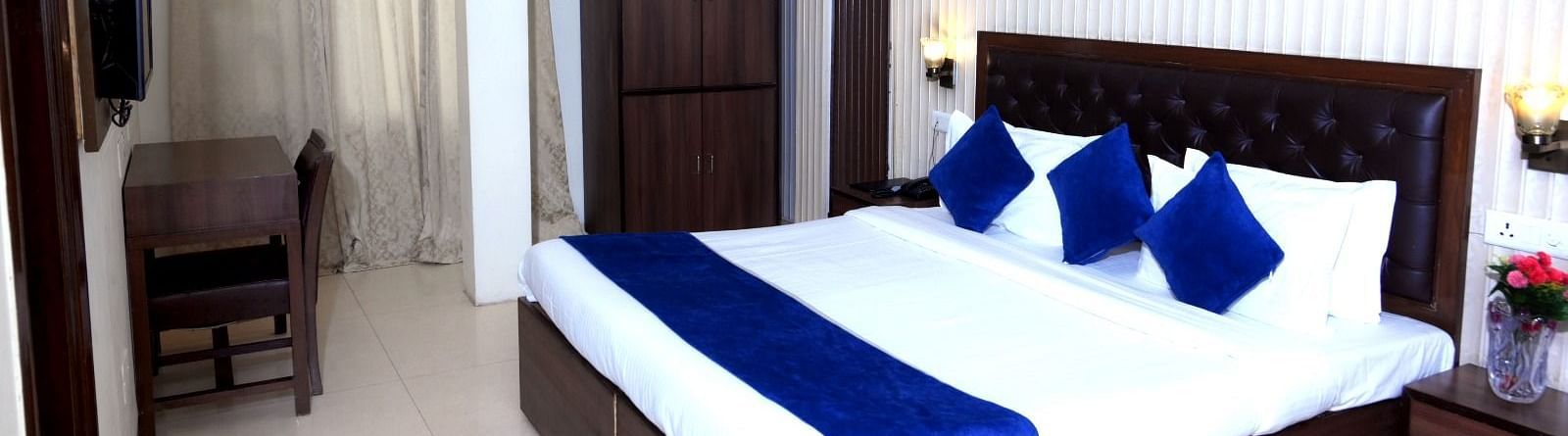  A cosy hotel room with a king-size bed, blue and white linens, wooden furniture, and soft lighting - Hotel Diamond Inn, Chandigarh