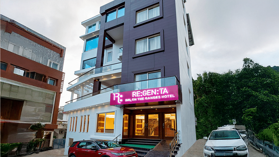 A wind angle shot of Regenta Inn DLS with a lush green hilly region in the background.