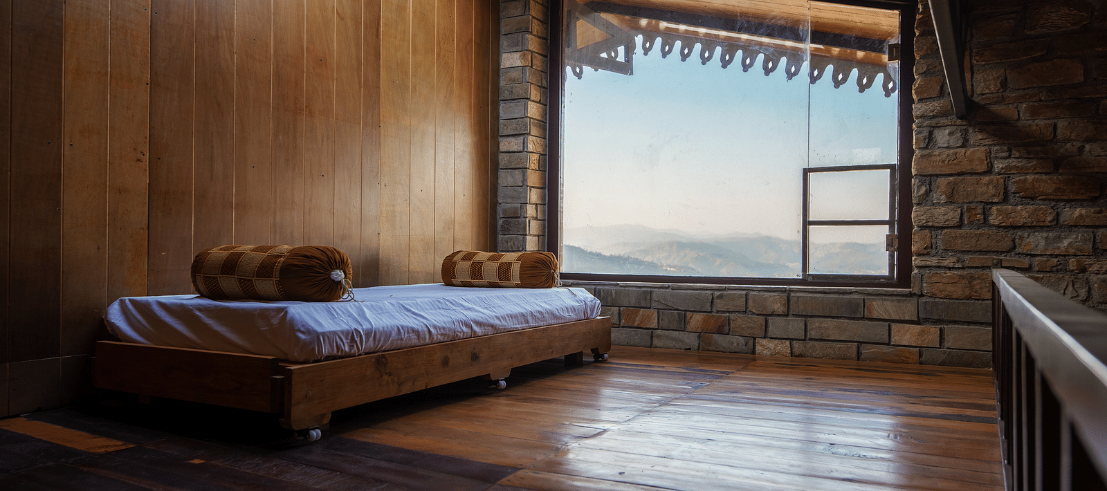 Rustic wooden bedroom interior with a bed and mountain view through a large window. - Blusalzz Homes The Himalayan Bungalow, Almora