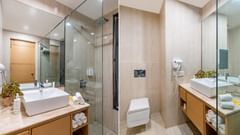 Superior twin bathroom with glass shower partition, large mirror, and wooden vanity at Golden Tulip, Udaipur.