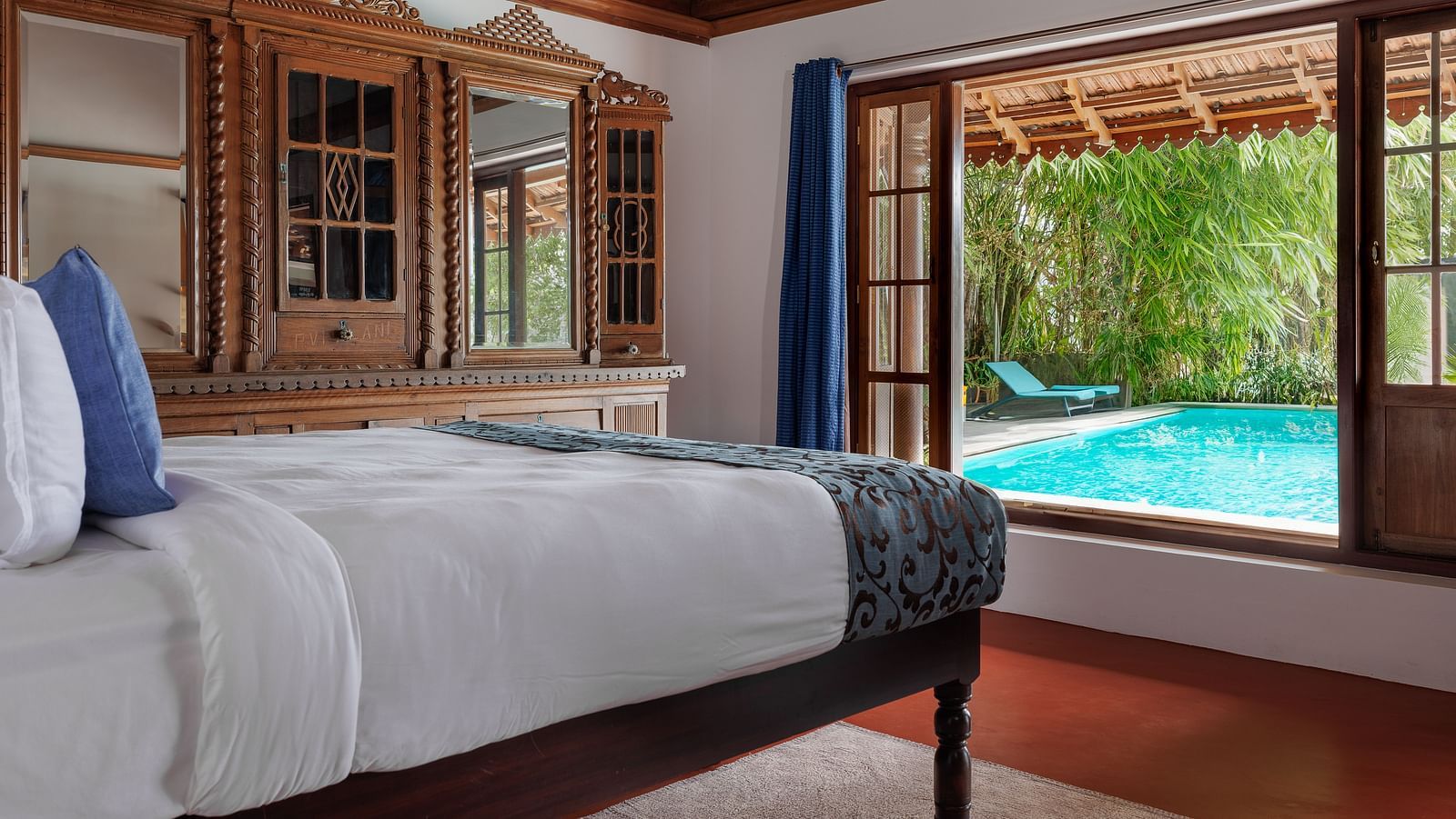 A shot of a room taken from an angle showcasing the bed facing a huge window with the view of the pool outside - BluSalzz Villas - Muhamma Resort, Alleppey