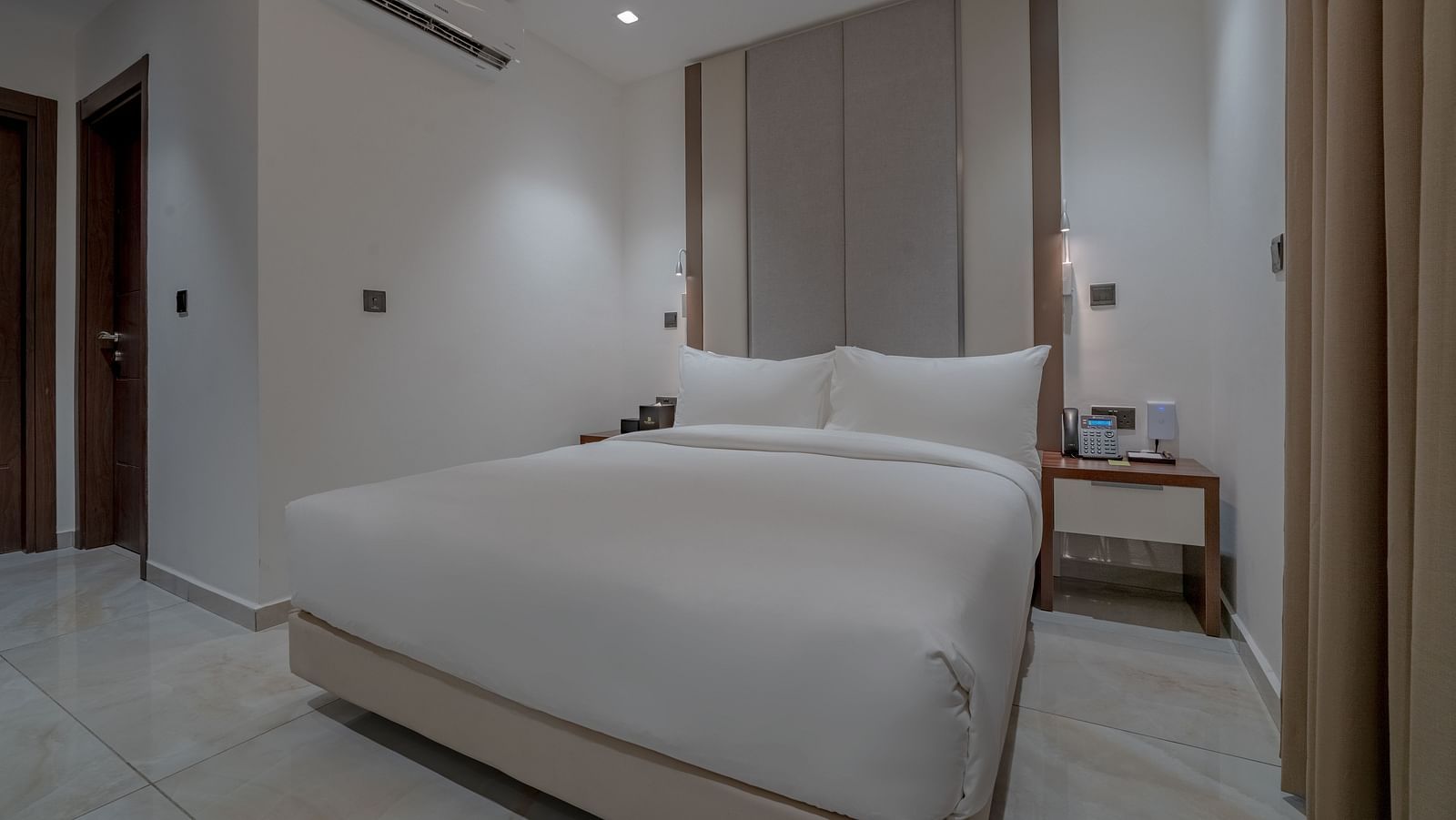 Elegant, spacious Deluxe Room with a comfortable bed, bedside tables, and modern decor. - The Pelican Hotel, Accra
