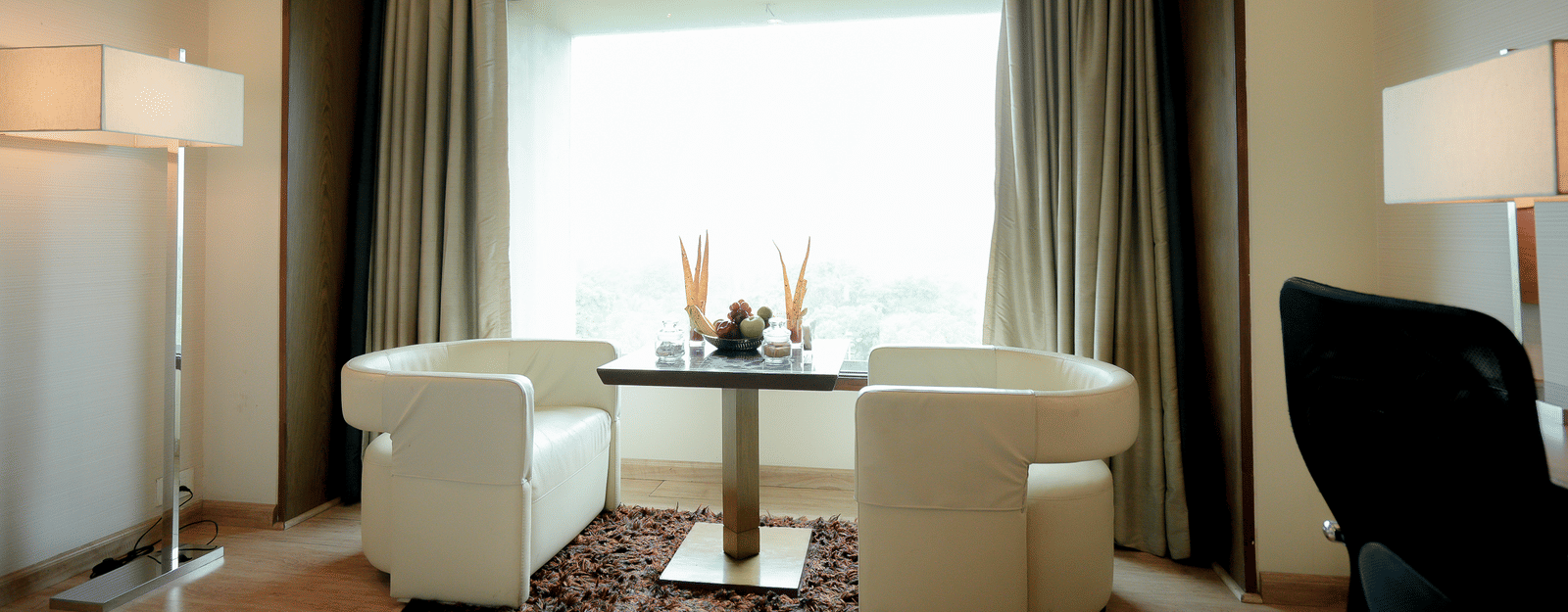 Plush seating area near window with table and armchairs – Narayani Heights Hotel & Resorts