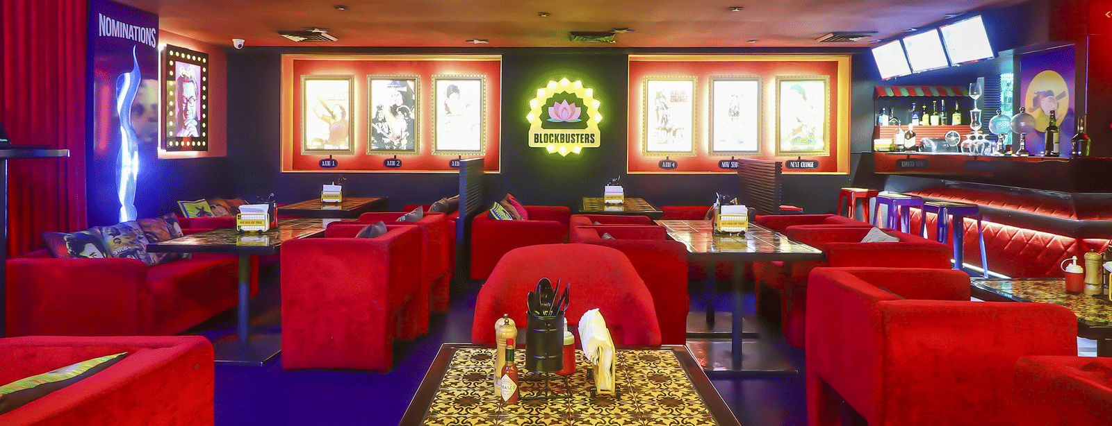 A dining area with red sofas, wall-mounted posters and bright ceiling lights at Infiniti Hotel, Indore.
