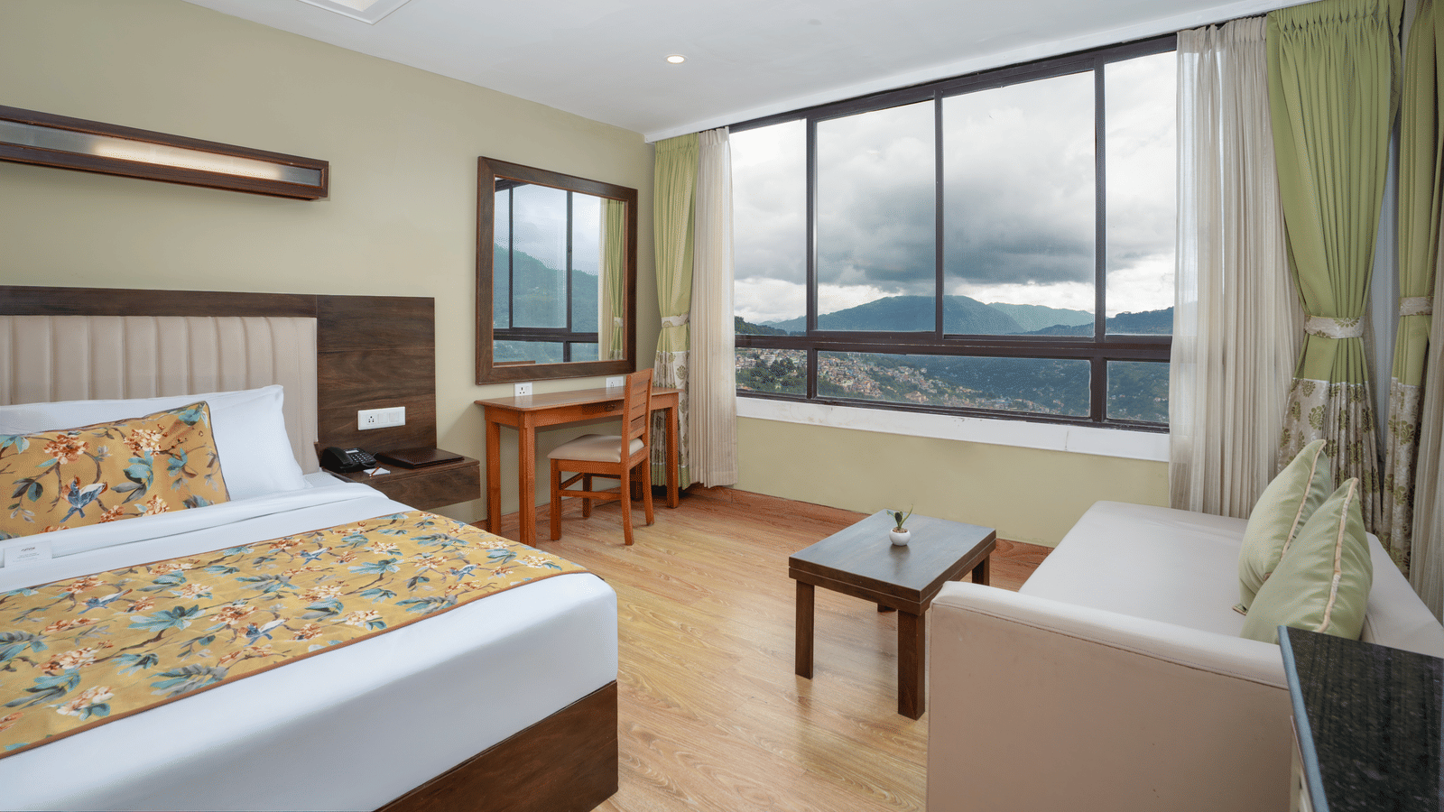 Deluxe Valley View Room at Summit North Star, Gangtok featuring a bed, a sofa with centre table, and a work desk and chair.