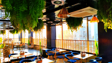 A wide-angle shot of Kensho rooftop pub at Leroy Grand, Yeshwanthpur, with sun rays filtering through the window besides the corner tables.