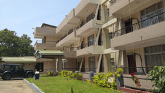 A view of the Polo Tura Hotel from a corner, showing its balconies, with a vehicle parked in front.