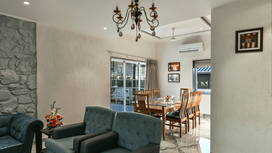 Spacious dining and lounge area, adorned with a chandelier, plush seating, and a cosy ambience – Maxxvalue Klub Klass Villa, Lonavala.