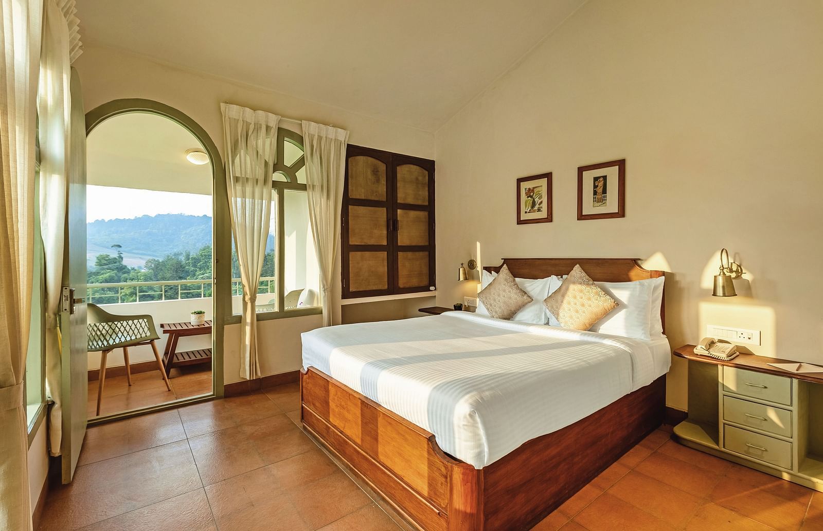 Bedroom at Mango Hill Shola, Ooty, with a double bed, wooden flooring, and an arched window offering an outdoor view.