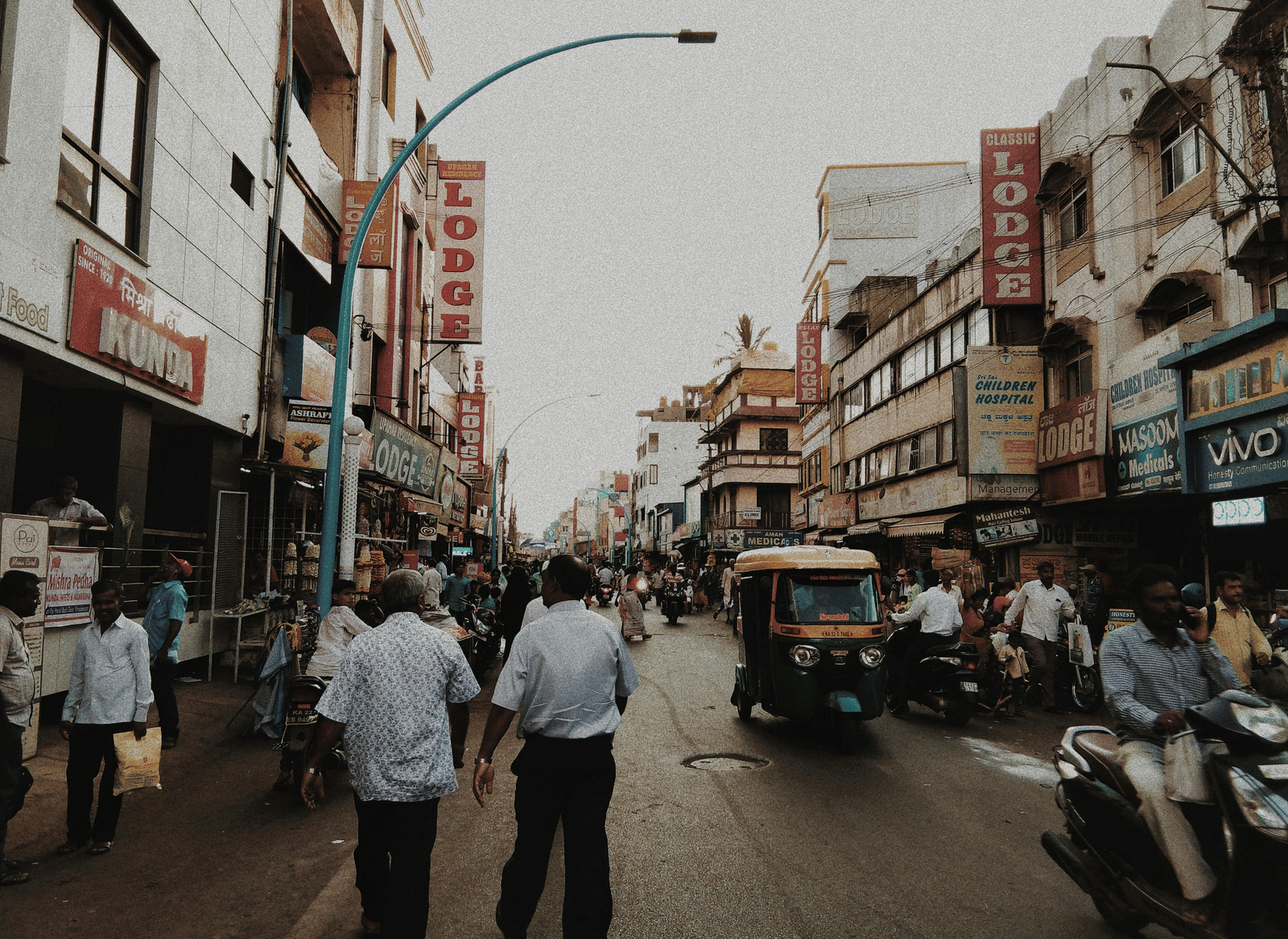 A busy street scene with vehicles, shops, and pedestrians.