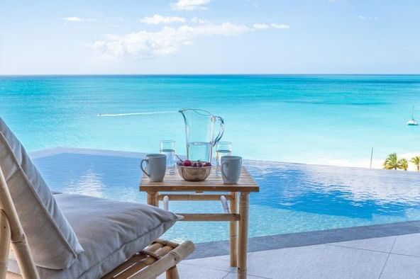 Infinity pool overlooking turquoise Caribbean waters at Tamarind Hills Resort and Villas, Antigua, with lounge chair and refreshments