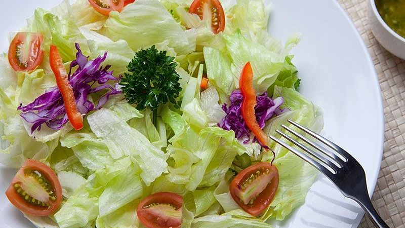 A close-up of a salad with lettuce, tomatoes, and herbs - Shreyas Retreat