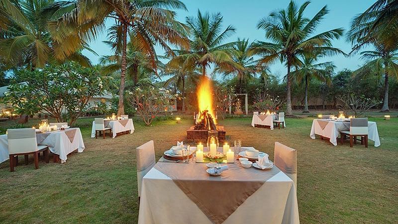A beautifully arranged outdoor dining setup near a bonfire with a beach view - Shreyas Retreat
