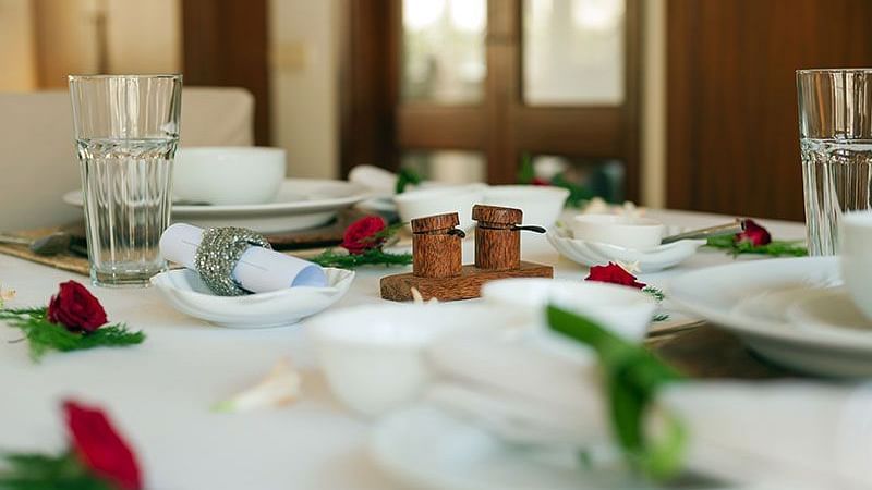 A table set with plates and cutlery, surrounded by windows - Shreyas Retreat