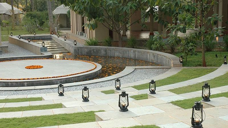 Garden with a circular water feature and lanterns, outdoor setting - Shreyas Retreat