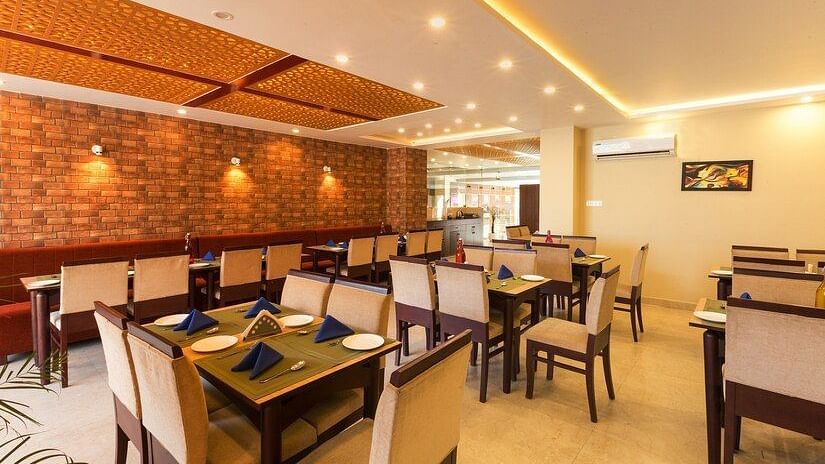 image of the indoor dining area with dining tables surrounded by off white cushioned chairs - ZENQ SIGNATURE INN, MCLEODGANJ