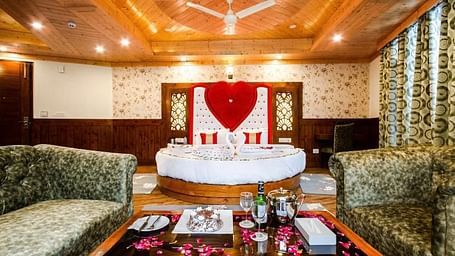 A cosy and inviting hotel room with a circular bed, comfortable sofas, and a romantic heart-shaped decoration | DLS La Serene Manali