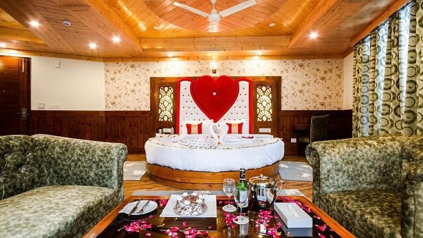 A cosy and inviting hotel room with a circular bed, comfortable sofas, and a romantic heart-shaped decoration | DLS La Serene Manali