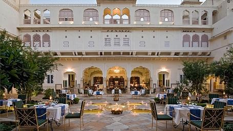 A verandah with comfrtable chairs and tables at Samode Haveli