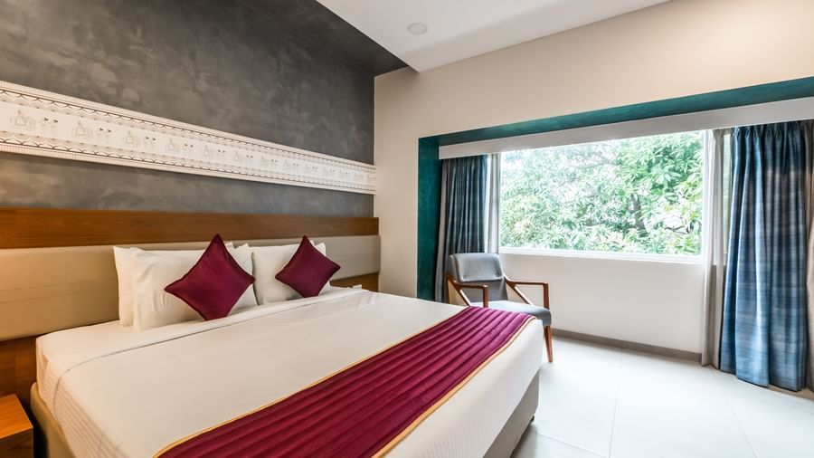 A bright hotel room with a large bed and ample natural light, providing a relaxing ambience at Shilton Dee Cee.