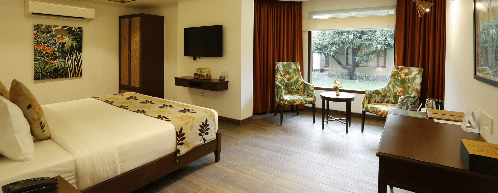 Hotel room featuring a cozy bed, wall-mounted TV, and a chair in the corner.