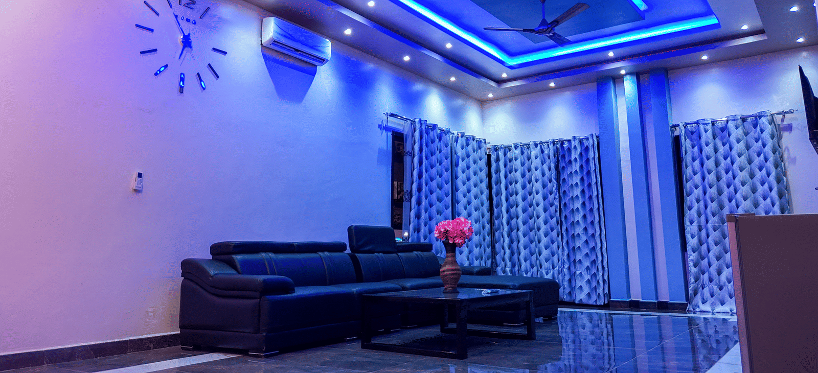 Spacious living room with blue ceiling lights, sofa, and ceiling-to-floor curtains - Luffu Club