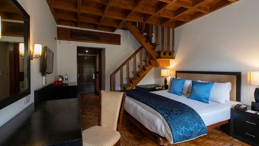 A room featuring a bed, tables, chairs and a TV - Mastiff Grand, Manali