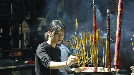Devotee lighting incense sticks during a prayer ritual.