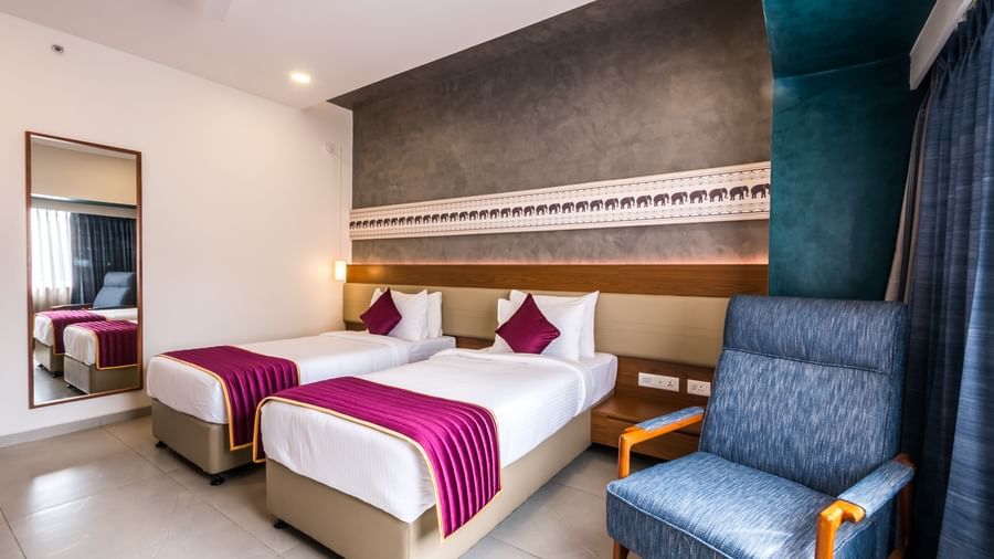 A well appointed hotel room featuring a large bed, an armchair, and a full length mirror at Shilton Dee Cee.