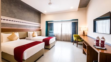 A spacious hotel room with a large bed and a comfortable seating area, offering a relaxing stay at Shilton Dee Cee.