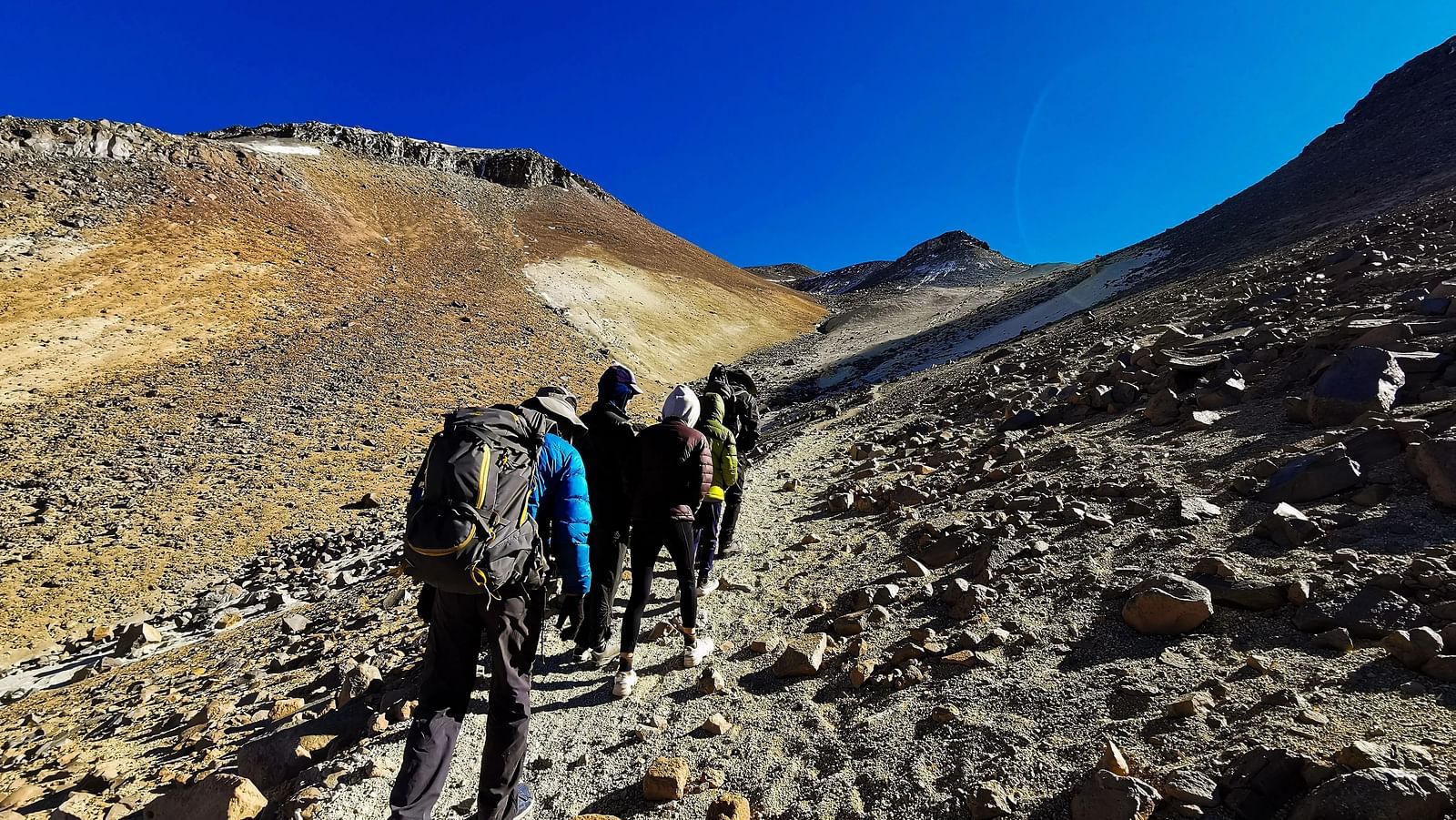 A group of people hiking in a mountain terrain with their backpacks.