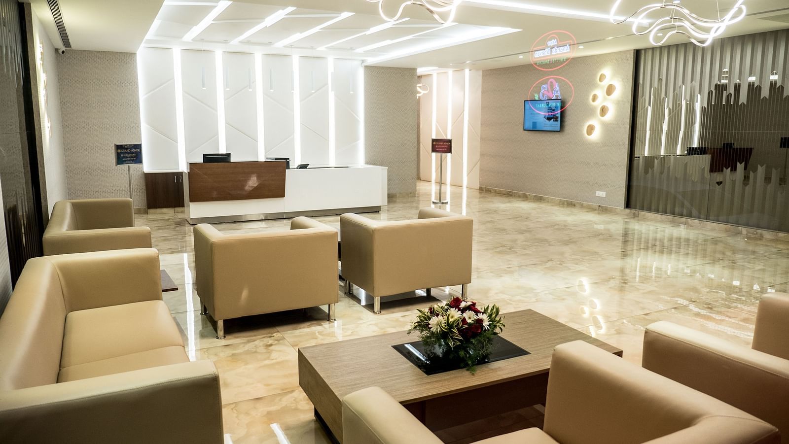 Lobby area with comfortable sofas and a reception desk at Grand Ashok, Thanjavur.