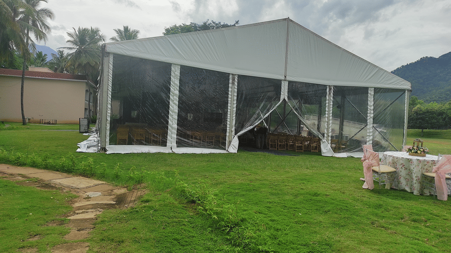An outdoor tent structure set up on a grassy area with mountains in the background, possibly used for an outdoor event or wedding reception - Black Thunder, Coimbatore