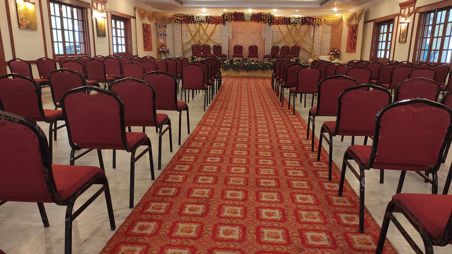 A view of an indoor conference or banquet hall with rows of red chairs lined up, ready for a formal meeting or event - Black Thunder, Coimbatore