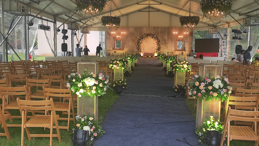 Outdoor wedding aisle with wooden chairs arranged on either side, leading to a decorated stage under a tent - Black Thunder, Coimbatore