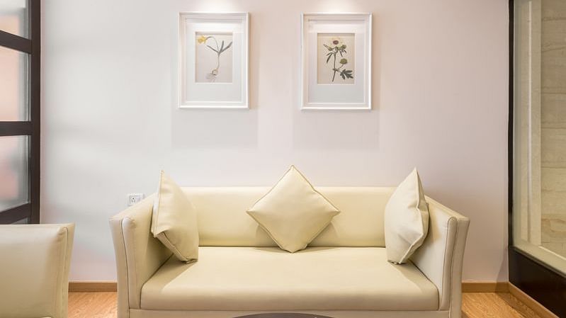 A cosy hotel suite corner with a sofa, coffee table and unique lamp hanging from the ceiling - TGI Grand Fortuna, Hosur
