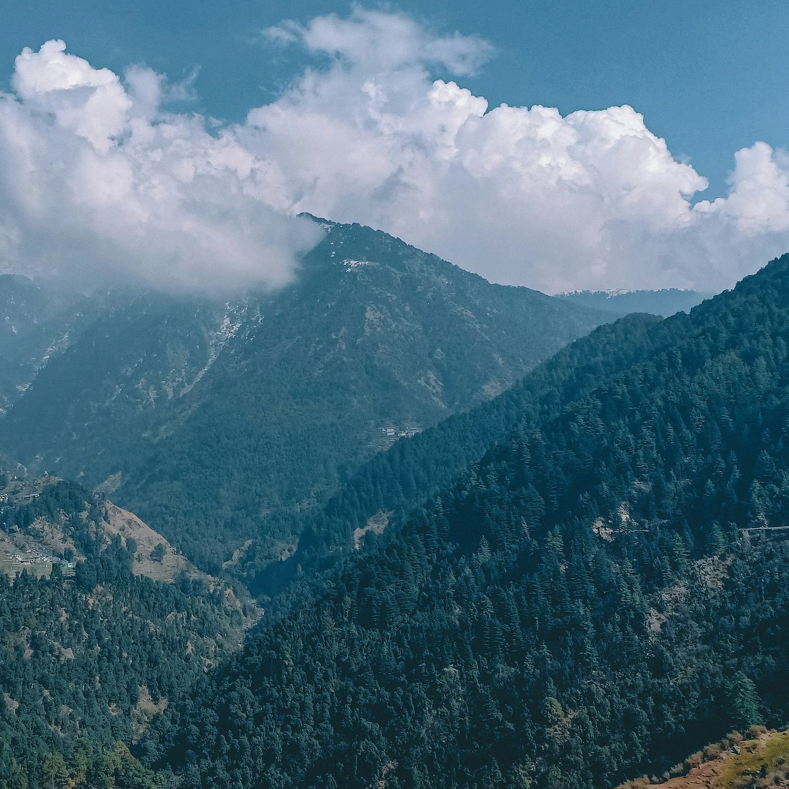 image featuring mountains covered in green vegetation with a clear sky with clouds in the background