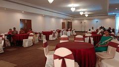 A banquet hall at the best resort in Bangalore, with people seated around round tables covered with cloth | Ramanashree California Resort