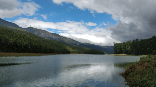 A serene lake surrounded by mountains under a partly cloudy sky.