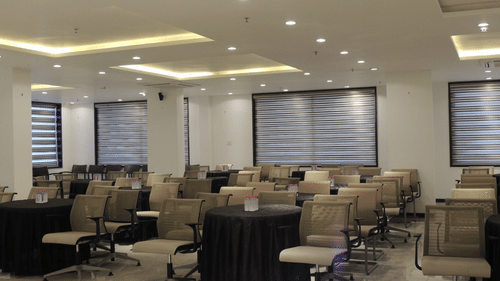 A large, empty conference room at Arawali Ananta Elite, Jaipur with rows of chairs facing a projector screen.