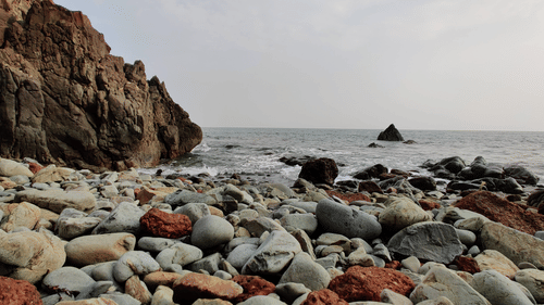 Rocks and rocky hills on the side with blue sky in the background at Butterfly Beach in Goa