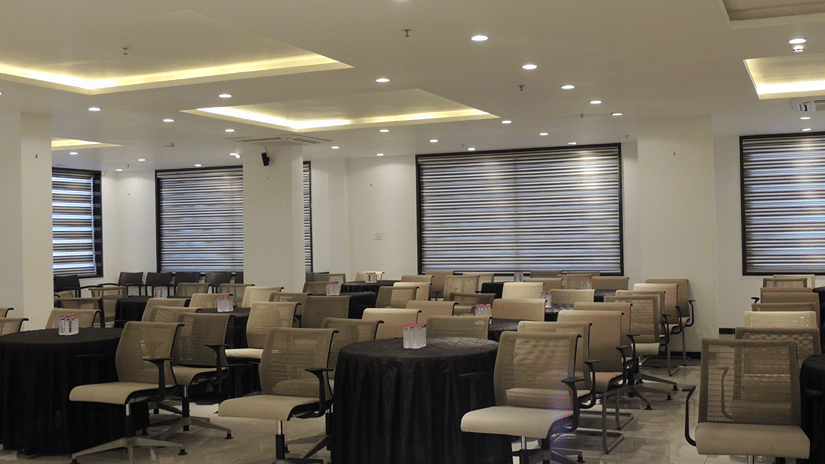 A modern meeting space featuring circular tables, grey chairs, and windows with horizontal blinds at Ananta Express, Katra.
