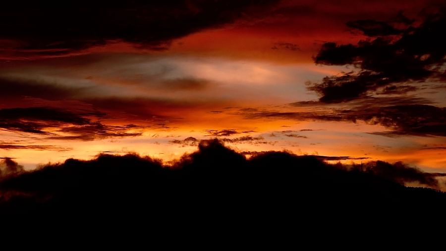 A dramatic sunset unfolds with dark, ominous clouds juxtaposed against a fiery red sky, creating a powerful and awe-inspiring spectacle, possibly a view from the resort's surroundings