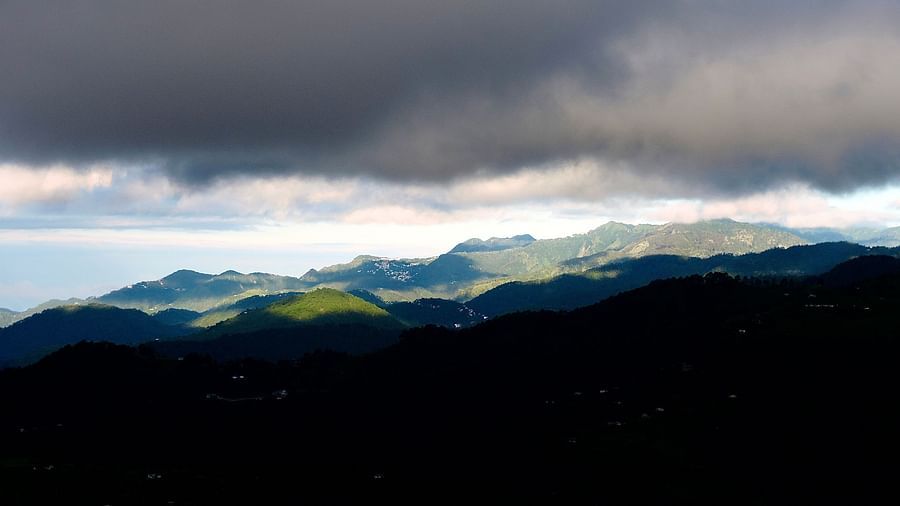 A cloudy mountain landscape, with a fleeting glimpse of sunlight breaking through the clouds, creates a moody and atmospheric scene, highlighting the natural beauty of the surrounding environment, possibly a view from the resort